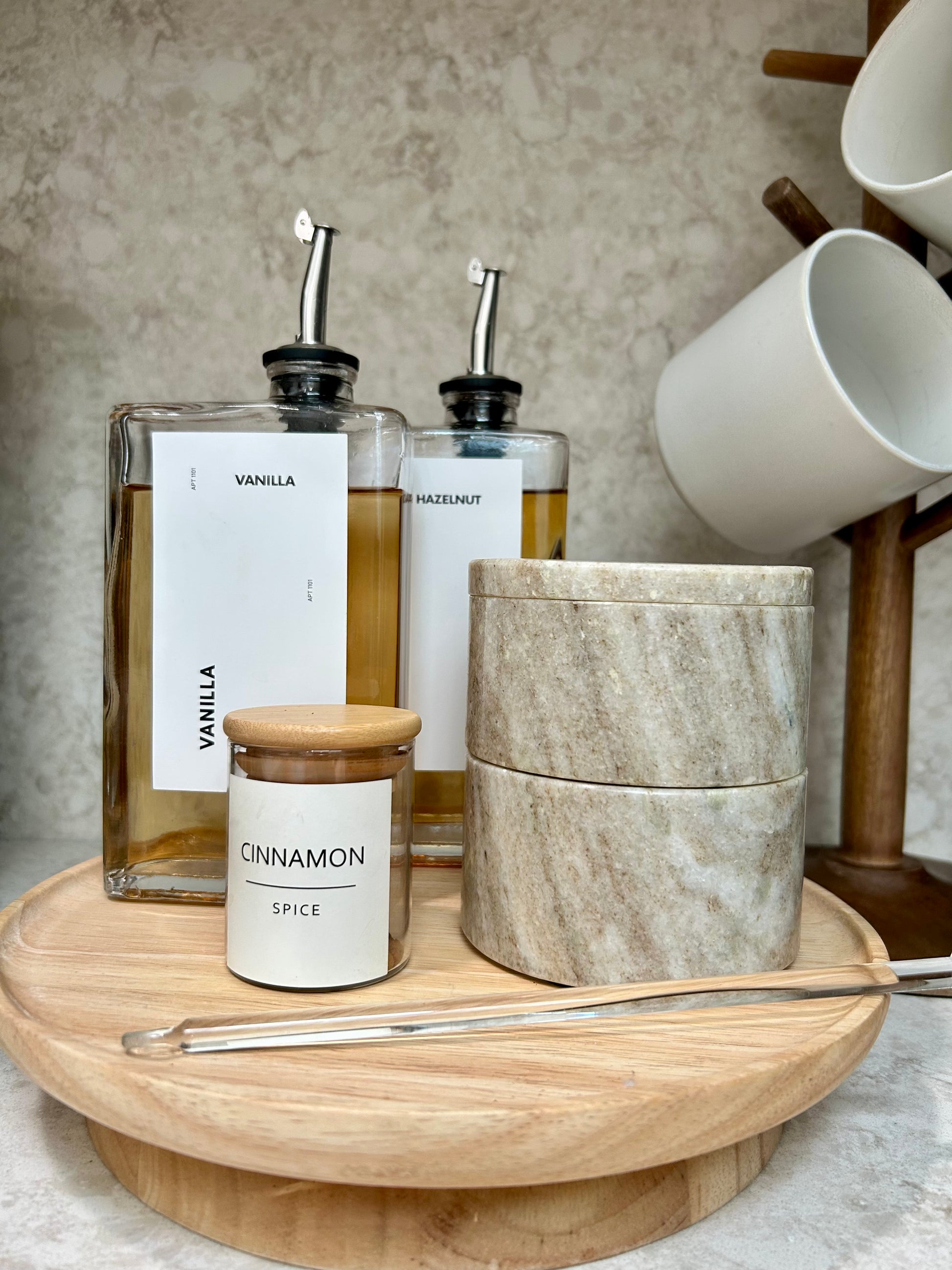 Spice jars and a container on a wooden tray with a neutral background
