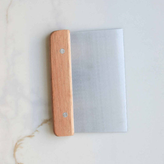 Wooden spatula with metal blade on a light marble background